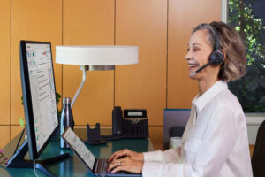 A Lady is working on a laptop and talking