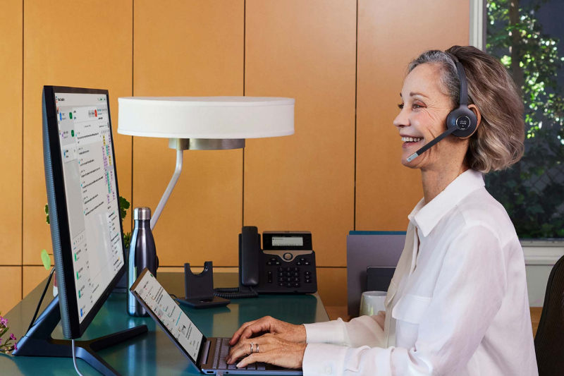 A Lady is working on a laptop and talking